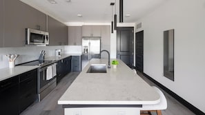 A modern kitchen with a central island, stainless steel appliances, and a minimalist design. - Landing | Chic 1BD - One Bedroom Apartment, Sleeps 2 (Nashville)