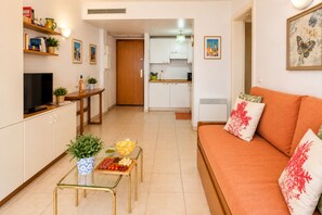 A compact living space with a sofa, a small dining table, a TV, and a kitchen area. - Intervalle, Atelier Du Repos Mental, Menton, France (Menton)
