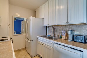 Una cocina con armarios blancos, un refrigerador, un lavavajillas, un fregadero y un tostador.
