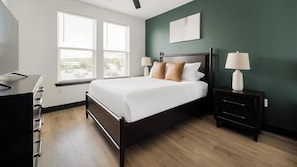 Quarto bem organizado com cama, mesas de cabeceira e escrivaninha.