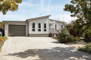 A residential building with a garage, a covered porch, and a paved driveway. - Salt Bush | Swim Spa | Close to Everything (Bicheno)