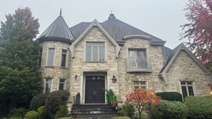 Ein Steinhaus mit einer schwarzen Haustür, einem Balkon und einem Schornstein.