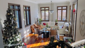 A spacious living room with a large Christmas tree, leather sofas, and a dining area. - Luxury Estate Home | Cinema & Sauna (Candiac)