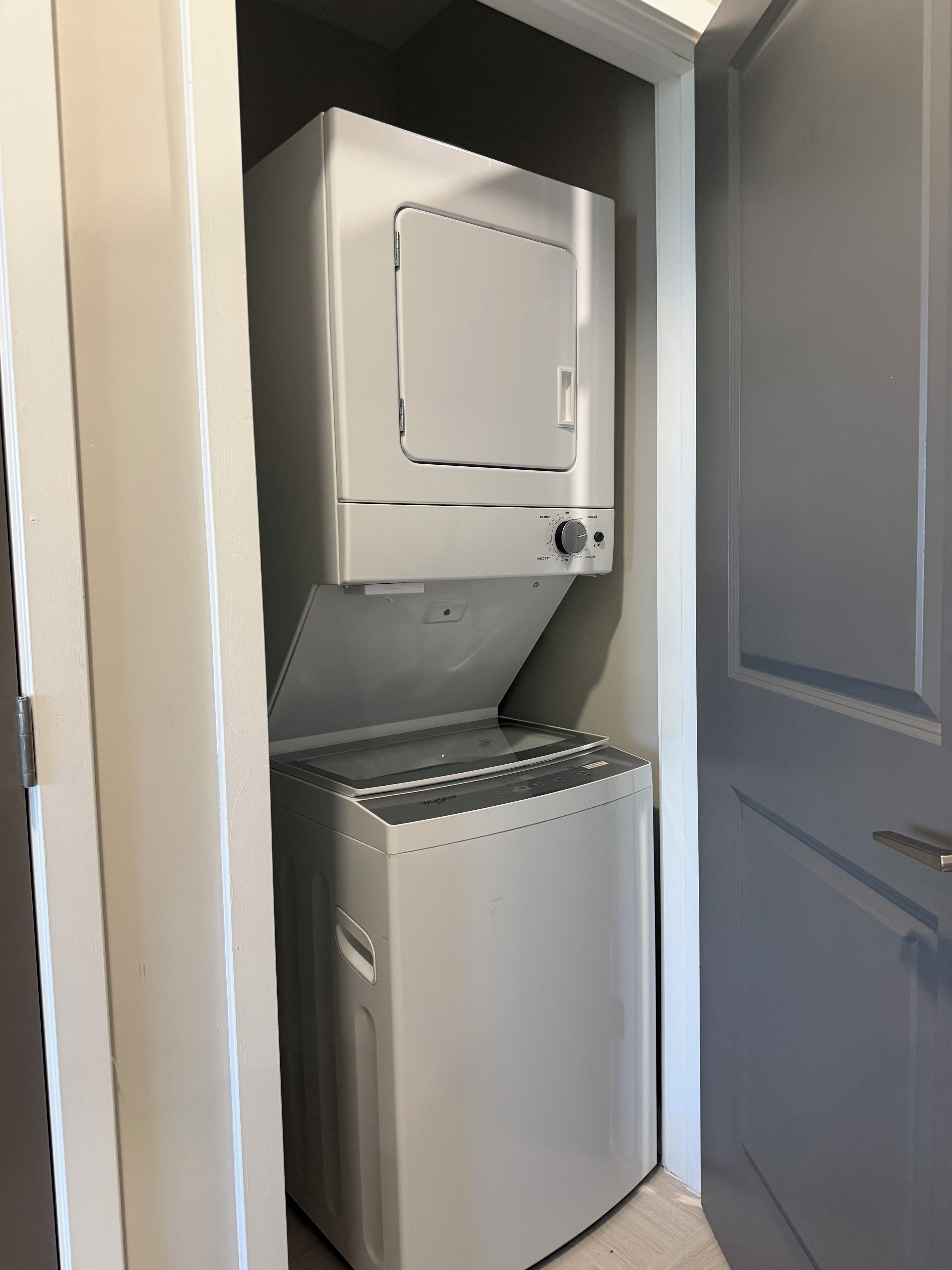 Une petite buanderie équipée d’un lave-linge et d’un sèche-linge à chargement frontal, d’une petite fenêtre et d’une porte.