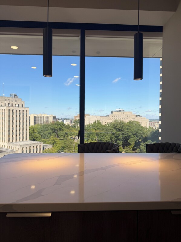 A modern interior with a large table and chairs, large windows with a cityscape view, and pendant lighting.