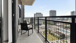 Varanda com vista para a cidade, uma cadeira e uma mesa.