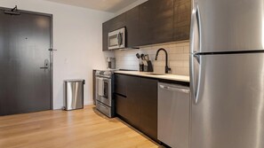 A modern kitchen with stainless steel appliances, a microwave, and a dishwasher. - Landing | Stunning Studio, Rooftop Lounge (Orlando)
