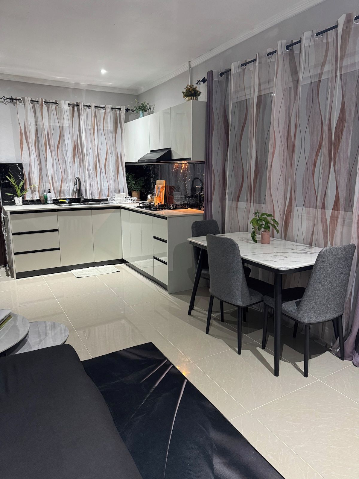 A modern kitchen with a dining area, featuring a central island, a built-in oven, and a stove.