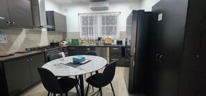 A compact kitchen with a dining table, chairs, and a refrigerator. - Park-view private rooms in a house in Clovelly Park, Adelaide, South Australia! (Clovelly Park)