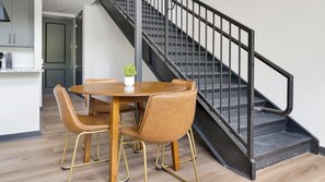 A modern kitchen with a dining area featuring a round wooden table and leather chairs. - Landing | Amazing 1BD, Courtyard, Gym (Atlanta)