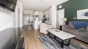 A modern living space with a kitchen, dining area, and a sofa. - Landing | Spectacular 2BD, Pool, Gym (Port Charlotte)
