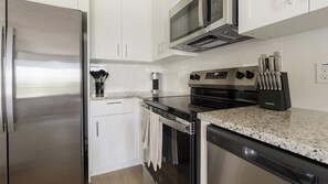 A modern kitchen with stainless steel appliances, white cabinetry, and granite countertops. - Landing | Beautiful 2BD, Gym, Clubhouse (Port Charlotte)