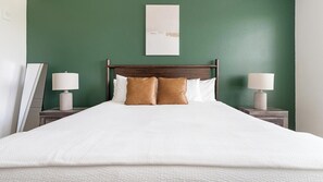 A bed with white bedding and two brown pillows, flanked by nightstands with lamps, in a room with green walls. - Landing | Beautiful 2BD, Gym, Clubhouse (Port Charlotte)