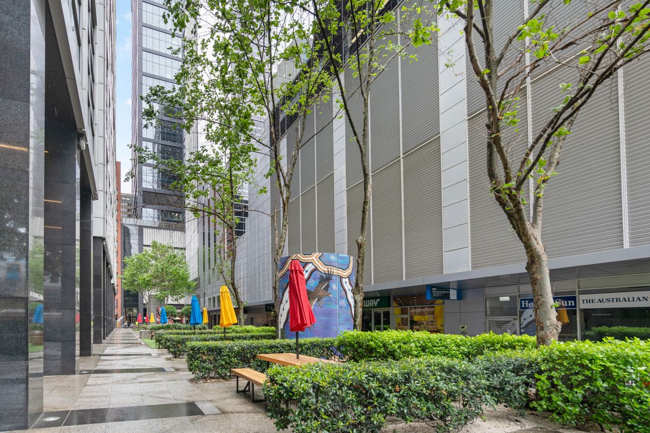 A modern urban courtyard with a pathway, benches, and a mural on a building facade.