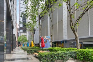 A modern urban courtyard with a pathway, benches, and a mural on a building facade. - Large 2-bedroom on Flinders (Melbourne)
