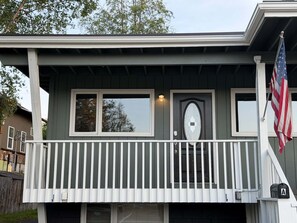 Ein zweigeschossiges Haus mit einem Balkon, einer Haustür und einer amerikanischen Flagge.