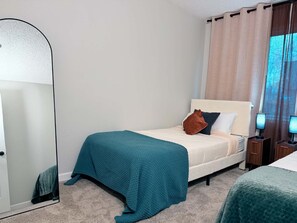 Une chambre d’hôtel avec un lit, une table de chevet, une lampe et une fenêtre avec des rideaux.
