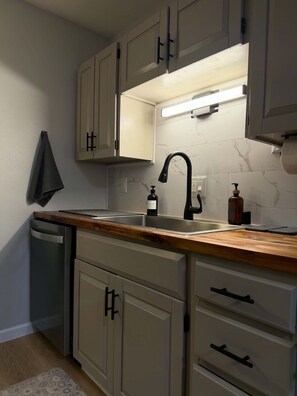 Eine Küche mit einer Holz Arbeitsplatte, einem Spülbecken und Schränken.