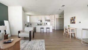 A modern kitchen with white cabinets, a central island, and bar stools. - Landing | Chic 1BD, Clubhouse, Gym (Port Charlotte)