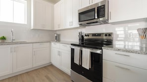 A modern kitchen with white cabinets, stainless steel appliances, and a granite countertop. - Landing | Chic 1BD, Clubhouse, Gym (Port Charlotte)
