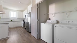 A modern kitchen with white cabinets, stainless steel appliances, and a wooden floor. - Landing | Chic 1BD, Clubhouse, Gym (Port Charlotte)