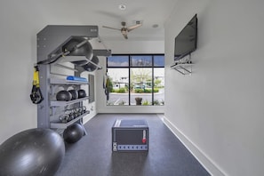 A gym with exercise equipment, a large exercise ball, and a TV on the wall. - Landing | Stylish 2BD, Gym (Destin)