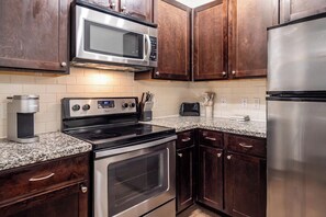 A kitchen with a stainless steel microwave, a coffee maker, a toaster, and a refrigerator. - Landing | Stylish 2BD, Gym (Destin)