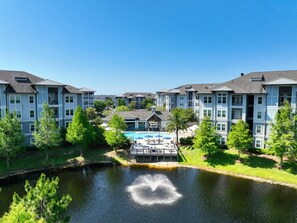 A multi-story hotel with a swimming pool and a fountain in the courtyard. - Landing | Stylish 2BD, Gym (Destin)