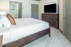 A bedroom with a bed, a dresser, a television, and a door. - Landing | Stylish 2BD, Gym (Destin)