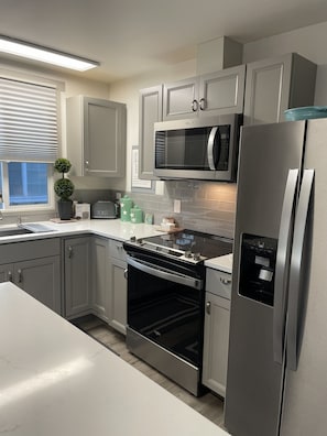 A modern kitchen with stainless steel appliances, a built-in oven, and a microwave. - Caspers Cozy Cottage- Whidbey Island getaway (Clinton)