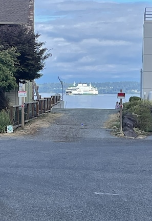 A road leading to a waterfront with a large ship docked in the distance. - Caspers Cozy Cottage- Whidbey Island getaway (Clinton)