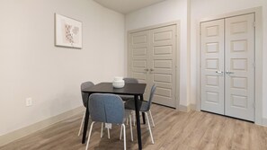 A dining area with a table and chairs, a framed picture on the wall, and a set of double doors. - Landing | Stunning 2BD, Rooftop Lounge, Clubhouse (Fort Worth)