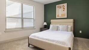 A bedroom with a bed, a nightstand, a lamp, a window with blinds, and a wall with a framed picture. - Landing | Stunning 2BD, Rooftop Lounge, Clubhouse (Fort Worth)