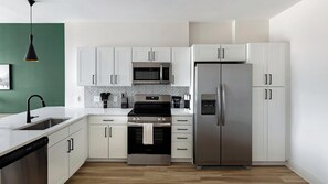 A modern kitchen with white cabinetry, stainless steel appliances, and a herringbone tile backsplash. - Landing | Spectacular 1BD, Gym, Clubhouse (Huntsville)