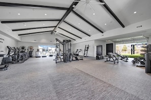 A spacious gym with various exercise equipment, a ceiling fan, and a view of the outdoors. - Landing | Spectacular 1BD, Gym, Clubhouse (Huntsville)