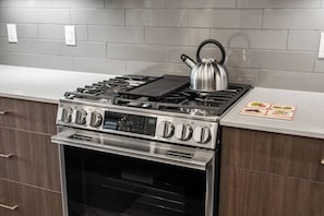 Een keuken met een roestvrijstalen fornuis, oven en een waterkoker op het fornuis.