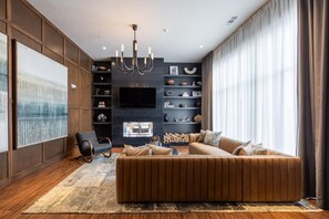 A modern living room with a sectional sofa, a mounted TV, and a fireplace. - Landing | Modern 1BD, Yoga Studio, Gym (Huntsville)