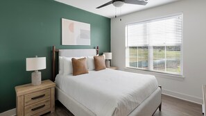 A bedroom with a bed, two bedside tables, a ceiling fan, a window with blinds, and a wall-mounted artwork. - Landing | Stunning 2BD, Clubhouse, Gym (Huntsville)