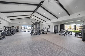 A spacious gym with various exercise equipment, a ceiling fan, and a view of the outdoors. - Landing | Modern 1BD, Game Room, Gym (Huntsville)