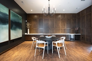 A modern dining area with a round table, white chairs, and a chandelier. - Landing | Modern 1BD, Game Room, Gym (Huntsville)