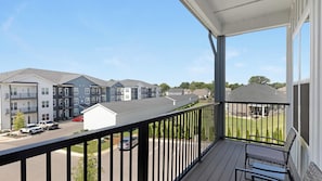 A residential building with a balcony, a parking area, and neighboring houses. - Landing | Beautiful 2BD, Yoga Studio, Game Room (Huntsville)