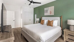 A bedroom with a bed, a nightstand, a lamp, a ceiling fan, and a door. - Landing | Beautiful 2BD, Gym, Clubhouse (Huntsville)