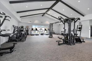 Ein Fitnessstudio mit Laufbändern, Kraftgeräten und einem Deckenventilator.