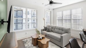 A modern living room with a grey sofa, wooden coffee table, and a ceiling fan. - Landing | Beautiful 2BD, Gym, Clubhouse (Huntsville)