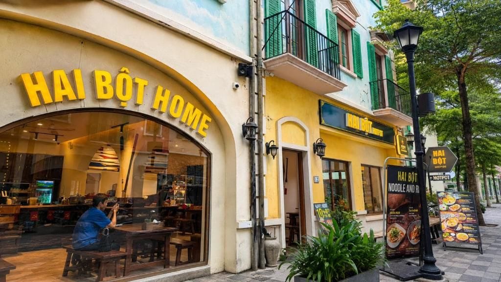 A restaurant named 'HAI BÒT HOME' with outdoor seating and a visible menu board.