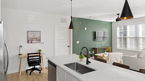 A modern kitchen with a white countertop, a black faucet, and a green accent wall. - Landing | Amazing 2BD, Game Room, Gym (Huntsville)