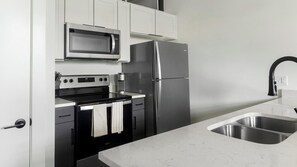 A modern kitchen with a stainless steel refrigerator, a microwave, and a stove. - Landing | Stunning 1BD, Gym (Gastonia)