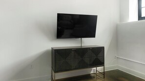 A television mounted on a cabinet with a cable running to the wall. - Landing | Stunning 1BD, Gym (Gastonia)
