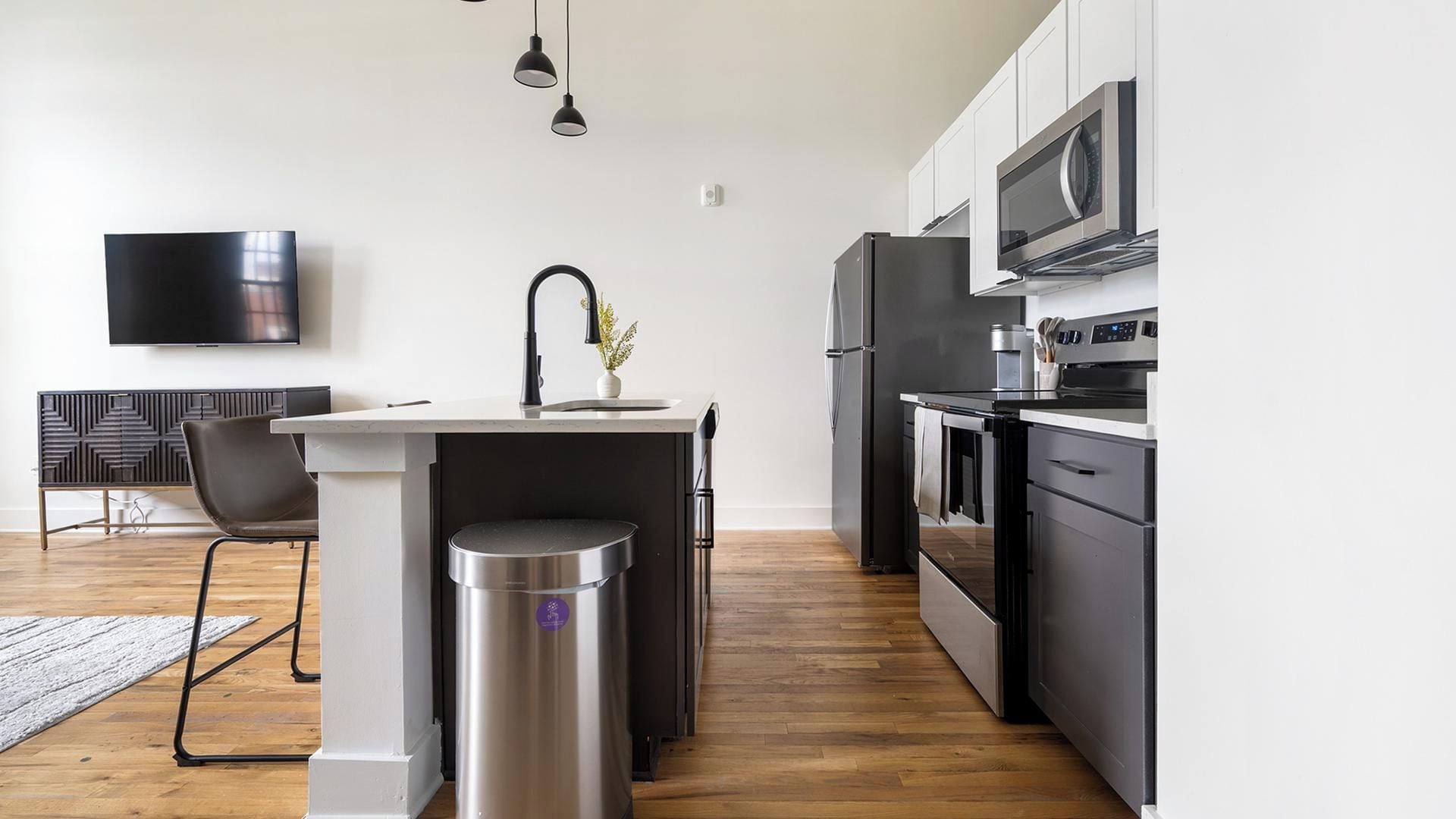 Una cocina moderna con una isla central, electrodomésticos de acero inoxidable y un televisor de pantalla plana montado en la pared.