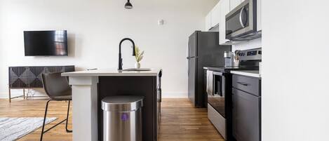 Una cocina moderna con una isla central, electrodomésticos de acero inoxidable y un televisor de pantalla plana montado en la pared.